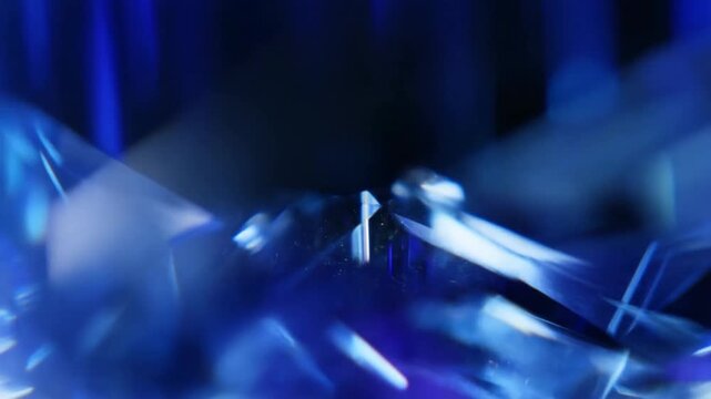 Macro tracking shot of gemstone facets reflecting and refracting blue light with shimmering glints on studio table close up