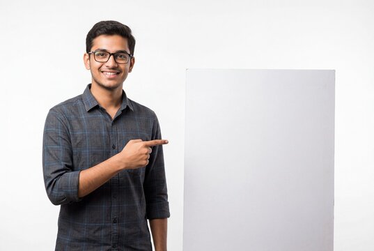Smiling young indian male student pointing to blank white board