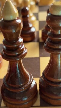 Close-up video showing a hand moving a black pawn from e7 to e5 on wooden chessboard during a chess game. Concept of strategy, opening play, tactical planning, concentration, intellectual competition