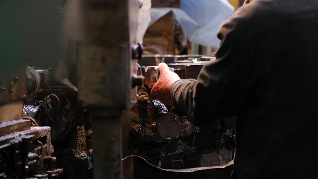 Wide view of a complex industrial machine tool covered in oil and metal shavings inside a professional manufacturing facility.