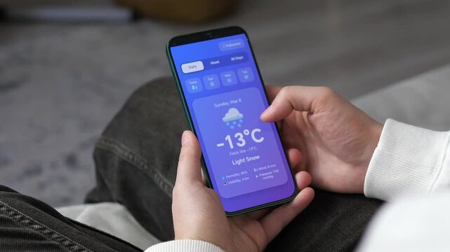 Checking winter weather forecast on a modern smartphone app. High-quality UI showing heavy snow and sub-zero temperatures. Perfect for tech reviews, seasonal news, and daily lifestyle vlogs. Clean