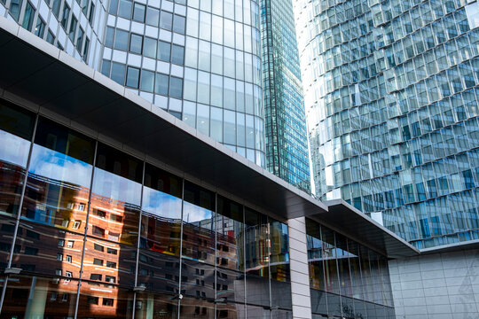 Glass facade reveals atrium with reflection while modern towers define La Defense paris skyline and urban architecture for finance business