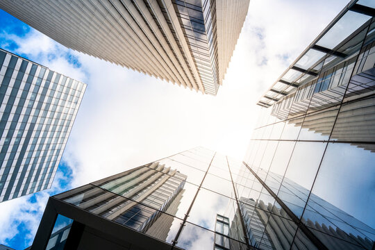 Sunflare and symmetry in La Defense paris as modern glass towers shape skyline and urban architecture for finance business district today