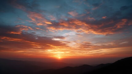Fototapeta premium Vibrant sunset sky filled with striking orange red and blue clouds over layered distant mountains