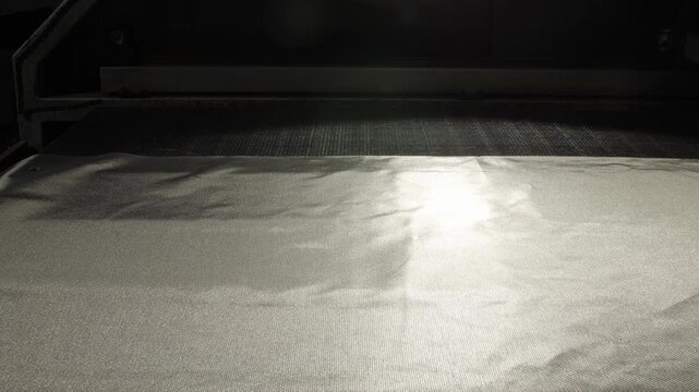Electromagnetic wave-blocking fabric across conveyor in workshop. Carefully arranged fabric to ensure prepped for upcoming cutting task
