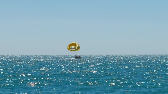 People beginning to go up parasailing and flying high above the turquoise Gulf of Mexico water