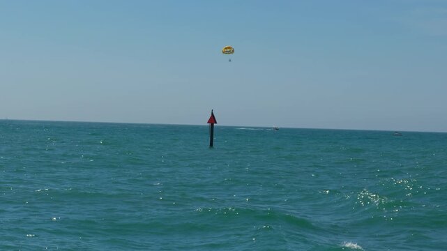 People parasailing in the distance high above the turquoise Gulf of Mexico water
