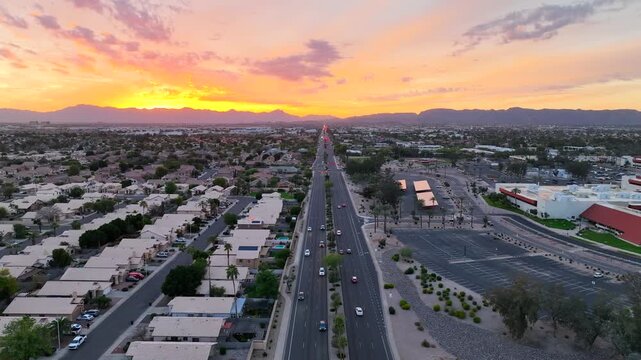 Aerial view of houses and a road during a vibrant sunset, with orange and purple hues blending in the sky, Chandler, Arizona, United States.
