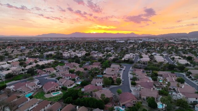 Aerial view of houses with roads winding through the neighborhood under a vibrant sunset sky, Chandler, Arizona, United States.
