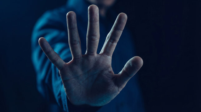 Person showing a stop gesture with a raised hand, symbolizing a warning, caution, or a plea for attention