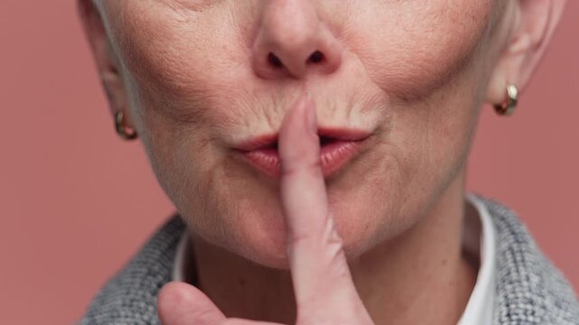 Senior Woman Showing Silence Gesture Close Up on Pink