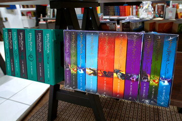 Naklejka premium Minsk, Belarus. Apr 12, 2026. Close up of multiple Harry Potter book boxed sets by J.K. Rowling on wooden display shelf in modern bookstore featuring colorful spines and various editions