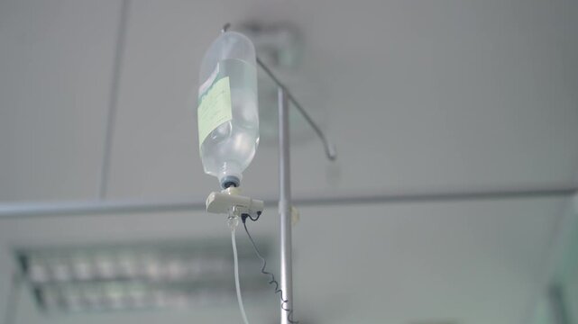 Close up of intravenous IV drip saline bottle hanging in hospital room, symbolizing medical treatment, hydration therapy, healthcare, and patient recovery in clinical environment.