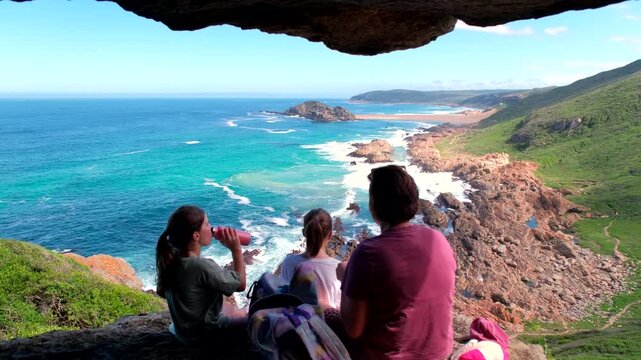 Mom and kids picnic in cave overlooking scenic Robberg Nature Reserve coastline
