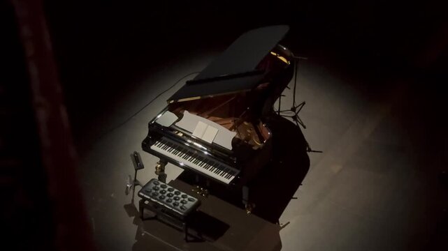 Grand piano and piano bench on empty wooden concert stage against plain wall. Studio stage setup. Classical music and live performance concept for poster and banner. 