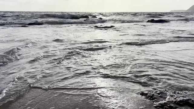 Cinematic golden hour waves washing over wet sand with sunset reflection at Goa beach