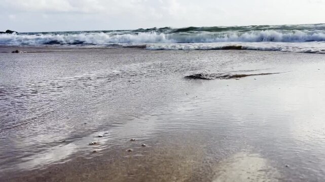 Close up of sea foam and bubbles washing over shoreline on a sunny day