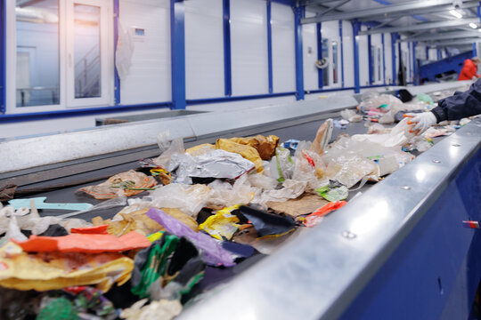 Recycling facility conveyor belt with mixed plastics and waste materials