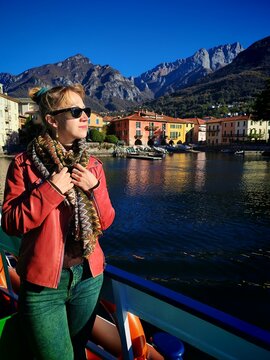 Como,Italy - October 28,2025:Young woman in red jacket show with finger at the colorful houses of village lake Como