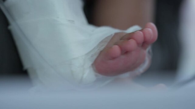Soft white bandage wraps a small baby foot. Tiny pink toes peek through gentle cloth. Crisp, clean wrap shows careful care. Baby's limb rests softly on a surface. Close-up highlights delicate