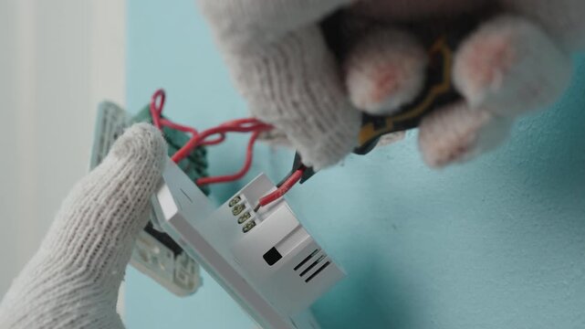 Technician uses pliers to installing modern switch, touch or smart phone-controlled on-off light, Smart Home.