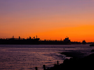 Fototapeta premium A big vessel floating on the water as the sun sets in the background
