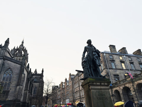 Adam Smith statue on the Royal Mile in Edinburgh, Scotland, UK, with historic buildings and St Giles Cathedral in the background