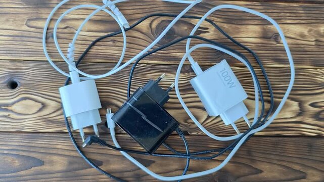 Different types of chargers and cables on a wooden table in bright light