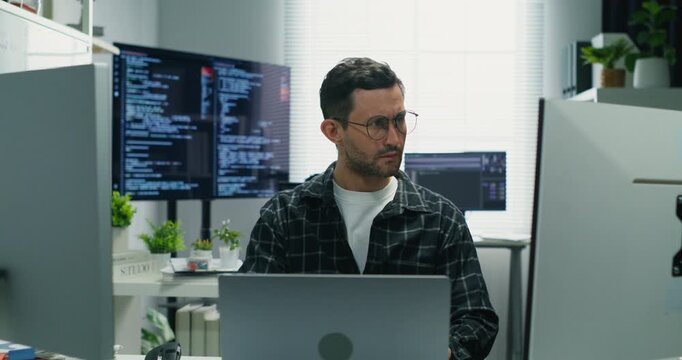 Caucasian programmer formulates security-focused software plans, coding network defenses, auditing databases, integrating AI prompts and guiding development and support teams.