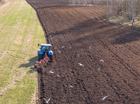 The tractor is preparing the soil before sowing. Aerial photo.