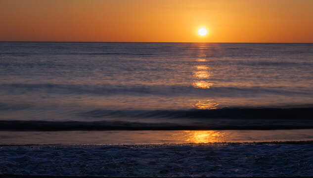 Warm sunset with soft waves and glowing light on the sea