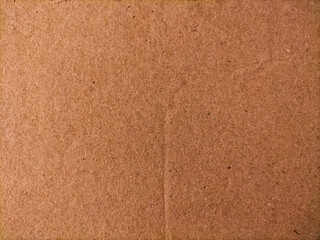 Fototapeta premium Brown cardboard surface with textural detail showing its fibrous material.