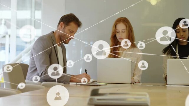 Team writing at table while one icon appearing growing network layering them mapping business links