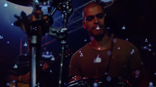 Camera shifting focus to drummer while guitarist playing, mic and icons drifting, streaming music