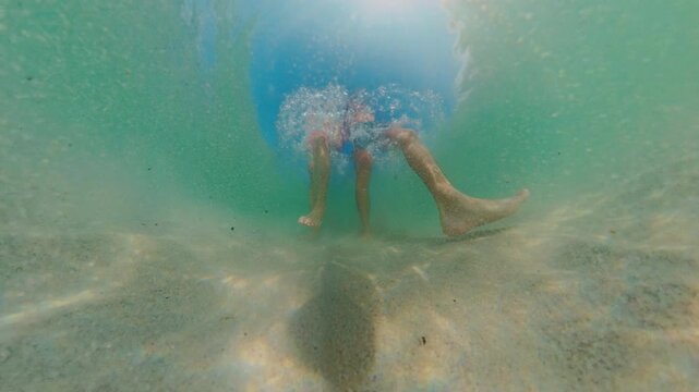 Underwater Low Angle View Couple Walking On Sandy Bottom With Strong Bubble Splash Above, Legs Moving Through Clear Water, Wide Angle Distortion, Tropical Seascape