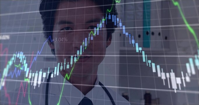 Viewing Japanese doctor in white coat, tie and stethoscope examining stock chart overlay in clinic