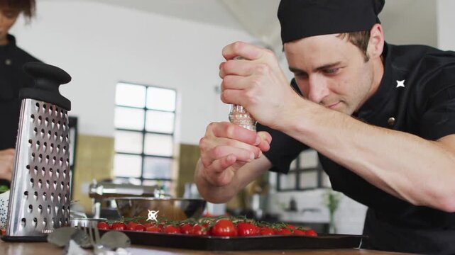 Chef using clear grinder in kitchen, seasoning tomatoes evenly, teal beams briefly masking center