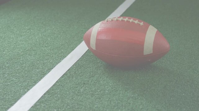 Camera executing small pan and zoom, revealing red football shifting near white sideline on turf