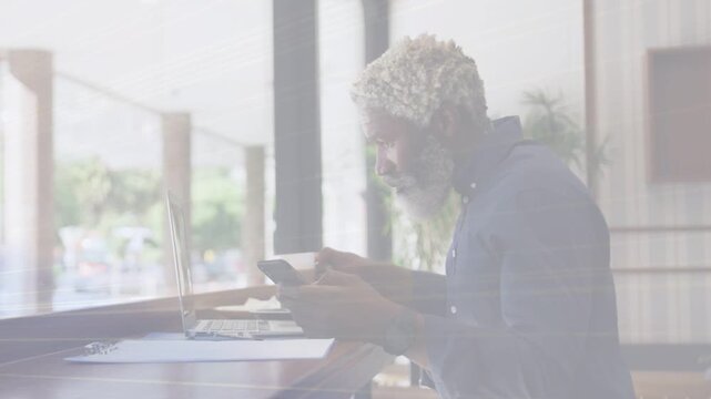 Man sipping mug, glancing laptop then picking phone, reading as animated overlay showing biz data