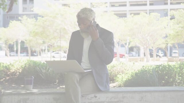 Man sitting on ledge taking incoming call, checking laptop for business with chart overlay emerging