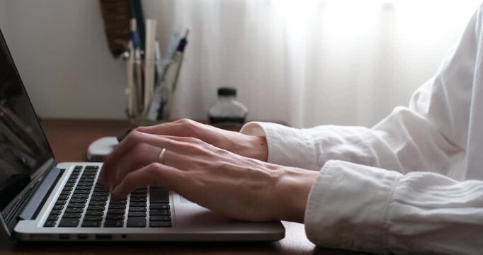 Typing on laptop keyboard at home desk, close-up hands, remote work lifestyle　自宅デスクでノートパソコンをタイピングする手元 リモートワークのイメージ