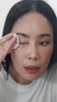 Woman removing makeup with cotton pad in mirror, skincare routine, clean healthy skin, beauty treatment, freshness, hygiene, and natural glowing complexion.
