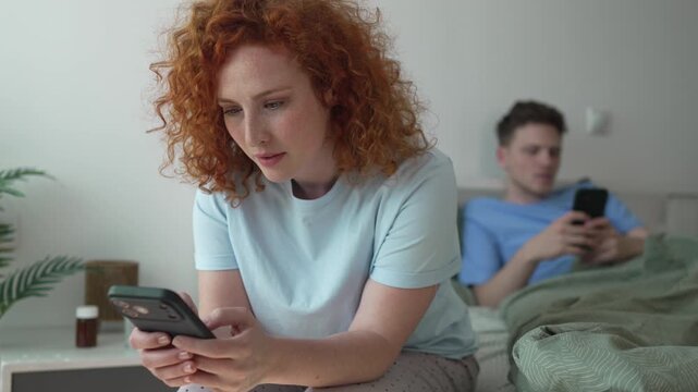 Distracted couple using smart phones in bed ignoring each other
