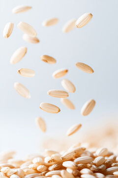 Raw rice seeds falling onto a pile. Floating uncooked cereal crop against a pale blue background