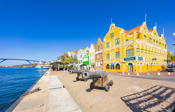 Willemctad, Curacao - 22.03.2026: Historic cannons on waterfront with Penha building and Queen Juliana Bridge in the background in Willemstad Curacao