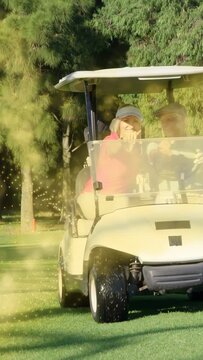 Vertical video: Man steering golf cart, woman pointing to greet camera while entering dust zone