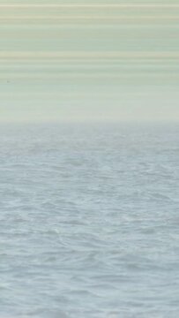 Vertical video: Open sea revealing horizon as camera panning, waves rippling to show calm expanse