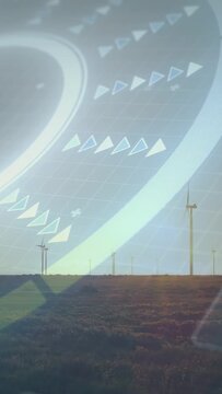 Vertical video: Sun low activating translucent HUD over wind farm, arrows drifting for turbine data
