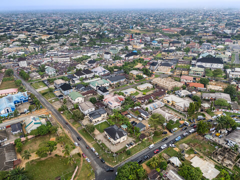 Aerial view of a sprawling urban landscape under an overcast sky, showcasing a mosaic of varied rooftops and bustling streets, Uyo, Akwa Ibom, Nigeria.