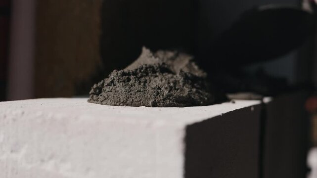 Applying mortar onto aerated concrete block with trowel close up
